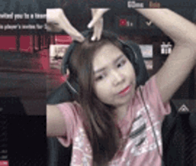 a woman wearing headphones and a pink shirt is sitting in a chair with her arms outstretched .