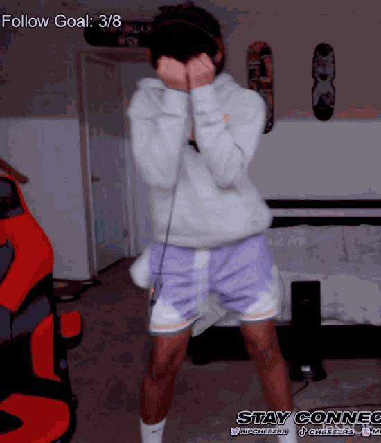 a person wearing purple shorts and a white hoodie is dancing in a room with the words follow goal 3/8 behind them
