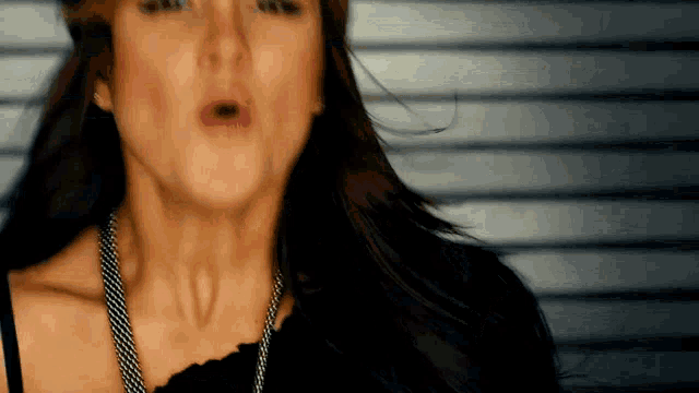 a close up of a woman 's face with long hair blowing in the wind