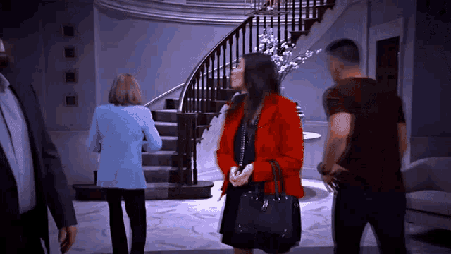 a woman in a red jacket is standing in front of a curved staircase