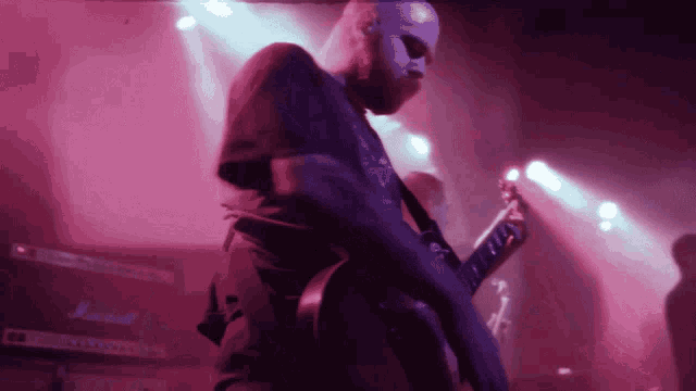 a man playing a guitar with a marshall amp in the background