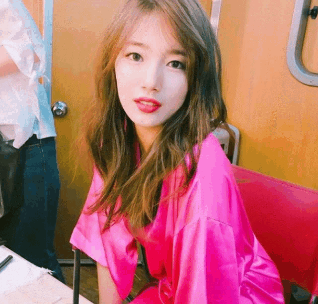 a woman in a pink robe sits in a chair