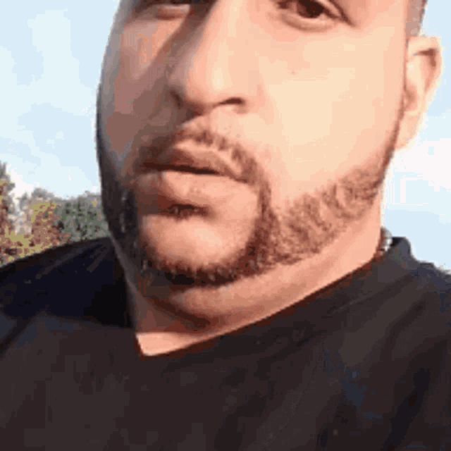 a man with a beard and a black shirt is making a funny face .