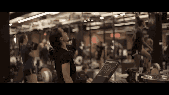 a woman is drinking from a bottle in a gym with a sign that says " open "