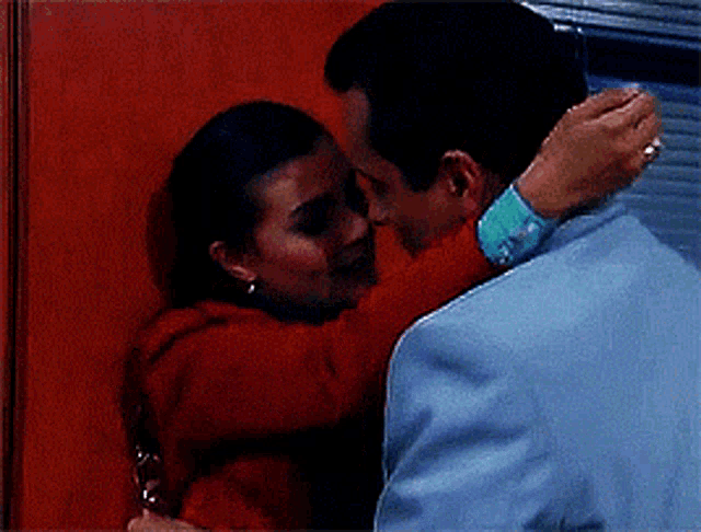 a man and a woman are hugging and kissing in a room