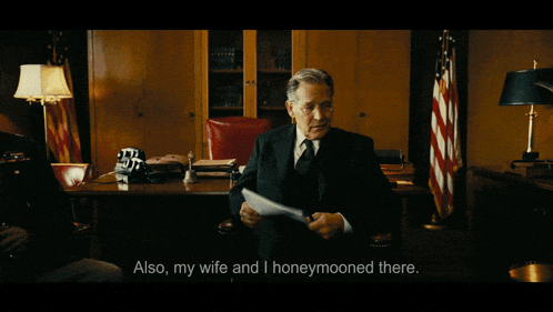 a man in a suit and tie is holding a piece of paper with the words also my wife and i honeymooned there below him