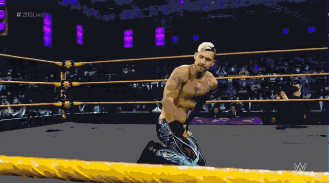 a shirtless wrestler is kneeling in a wrestling ring with the hashtag # 205live