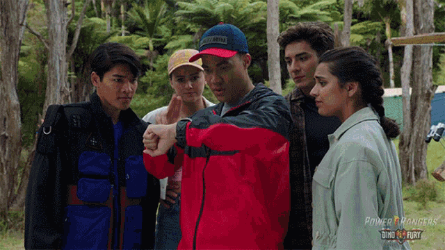 a group of people are standing around a man wearing a red jacket that says power rangers on it