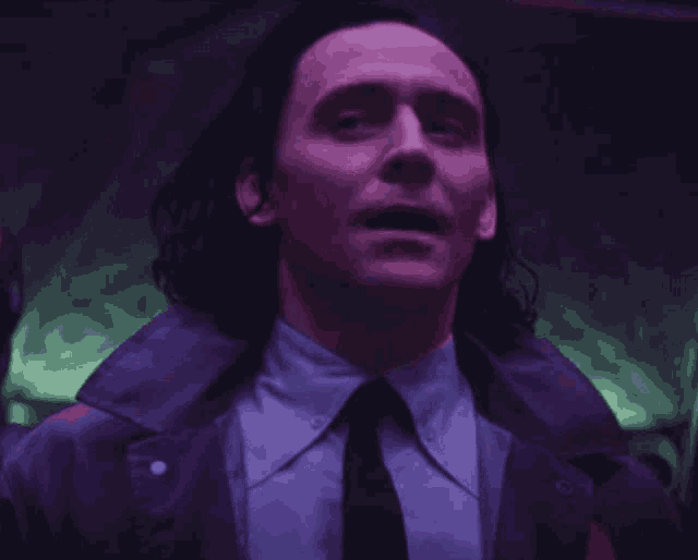 a man in a suit and tie is standing in a dark room .
