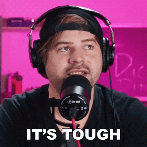a man wearing headphones and a microphone says it 's tough in front of a pink background