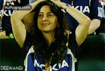 a woman wearing a blue nokia shirt is holding her hair .