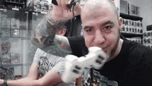 a man with a tattoo on his arm is holding a spider in his mouth while playing a video game .