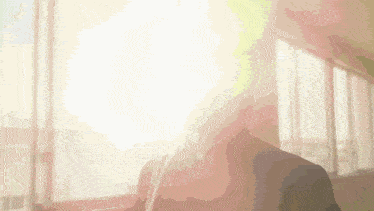 a blurred image of a person standing in front of a window with the sun shining through it