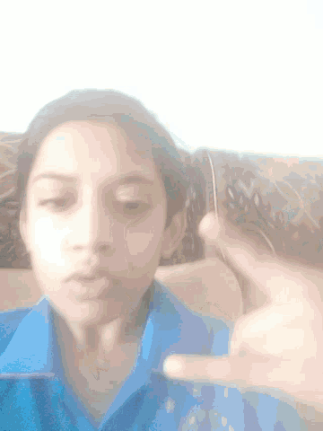 a girl in a blue shirt is giving a middle finger