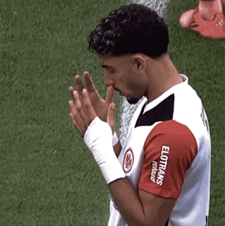 a man wearing a red and white elotrans jersey is praying on a field