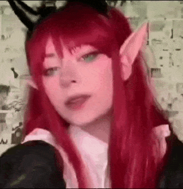 a girl with red hair and elf ears is wearing a cat headband and taking a selfie .