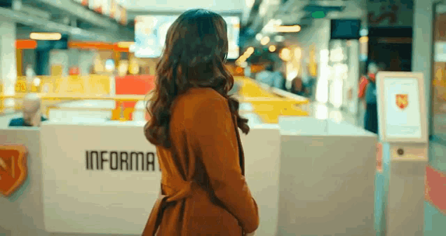 a woman is standing in front of a information desk in an airport .