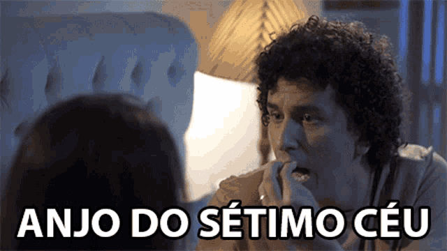 a man with curly hair is talking to a woman with the words anjo do setimo ceu written below him