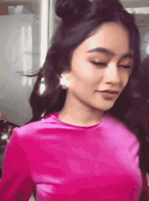 a close up of a woman wearing a pink shirt and earrings