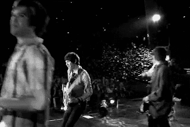 a man is holding a guitar over his head while dancing on a stage in front of a crowd .