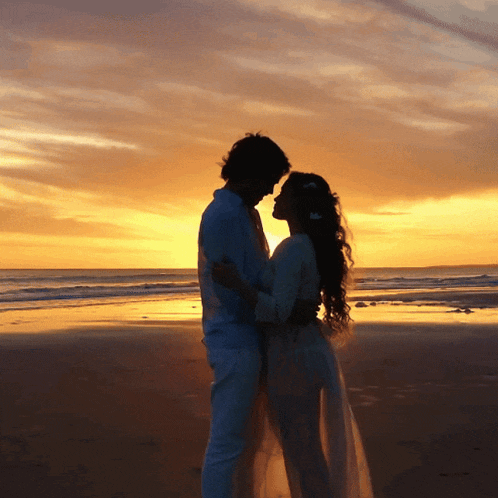 a silhouette of a man and a woman on a beach at sunset