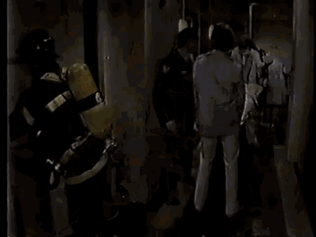 a man in a blue shirt is standing in a hallway with a fireman