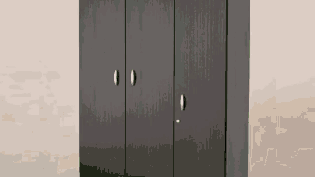 a black wardrobe with three doors and a key in the lock