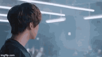 a man is standing in front of a crowd in a dark room with a lot of lights .