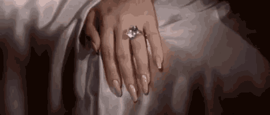 a close up of a woman 's hand wearing a diamond ring .