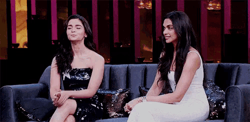 two women are sitting next to each other on a couch and talking .
