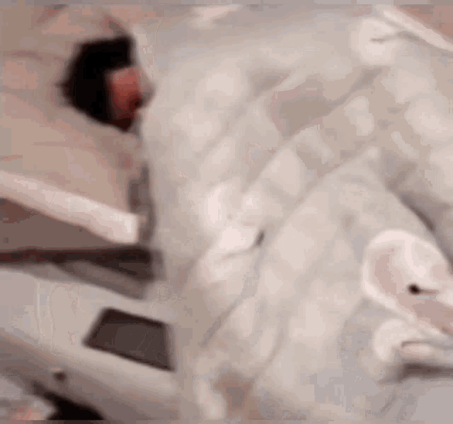 a person is laying on a bed with a blanket and a tablet on the bed .