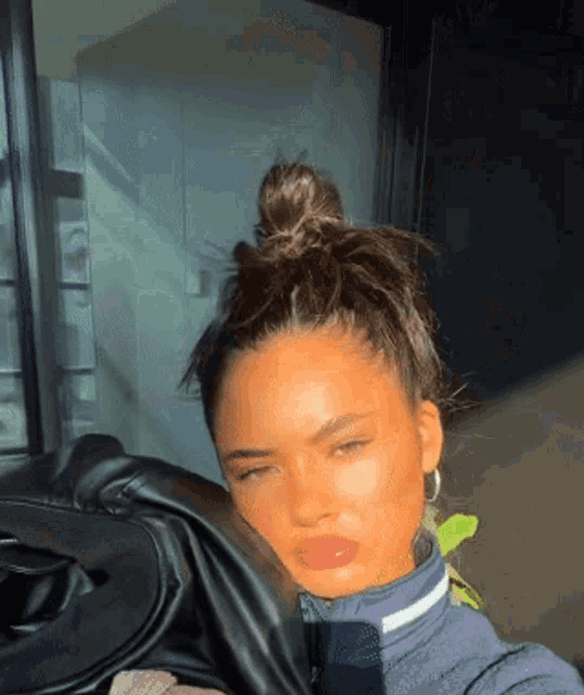 a woman is taking a selfie with her eyes closed and her hair in a bun