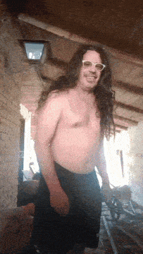 a shirtless man with long hair wearing sunglasses