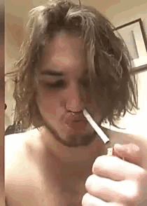 a young man with long hair is smoking a cigarette while holding a lighter .