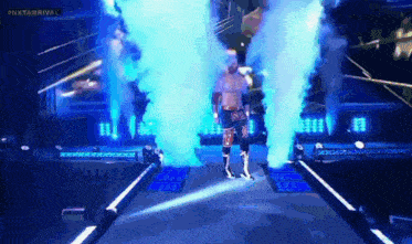 a wrestler is walking through a tunnel with blue smoke coming out of it ..