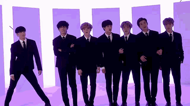 a group of men in suits and ties are standing in front of purple walls