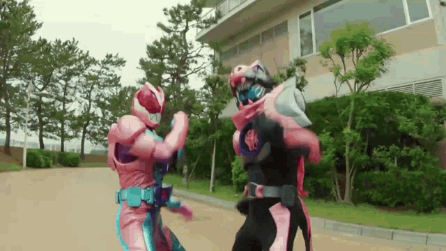 a couple of superheros are fighting each other in front of a building .