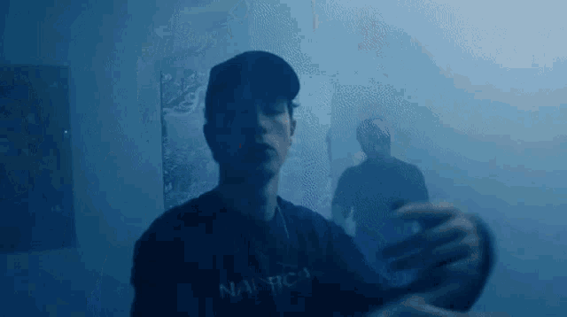 a man in a nautica shirt is standing in a room with smoke coming out of the walls .