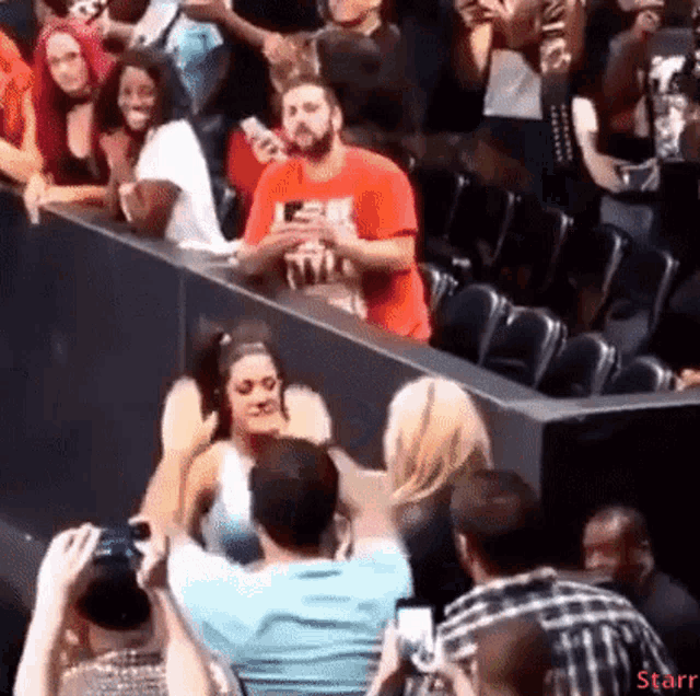 a man in a red shirt is taking a picture of a woman in a crowd .