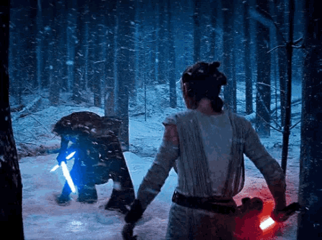 a woman is holding a lightsaber in the snow while standing next to a man holding a lightsaber .