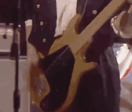 a man in a suit is playing a bass guitar in front of a microphone .