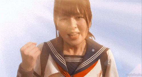a girl in a sailor uniform is making a fist in the air