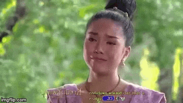 a woman in a purple dress is crying in front of a green forest .