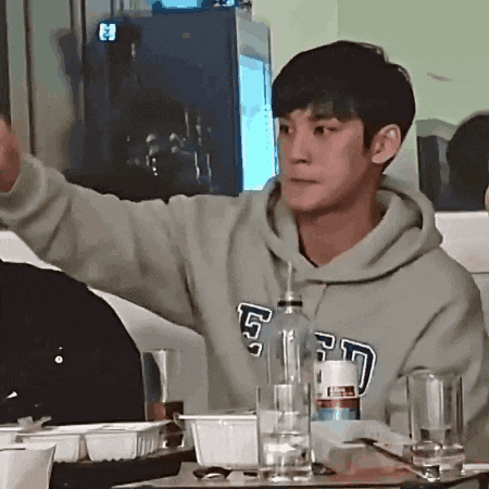 a man wearing a gap sweatshirt is sitting at a table with a bottle of water