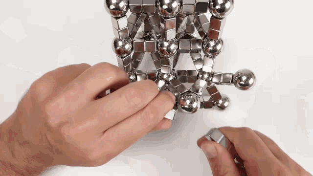 a person playing with a stack of metal balls