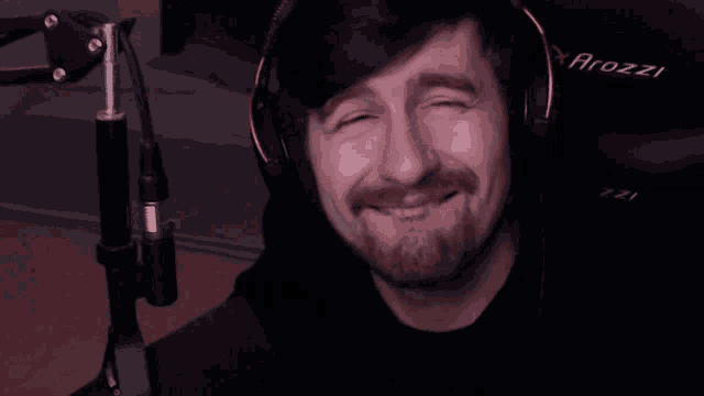 a man with a beard wearing a pair of arozz headphones