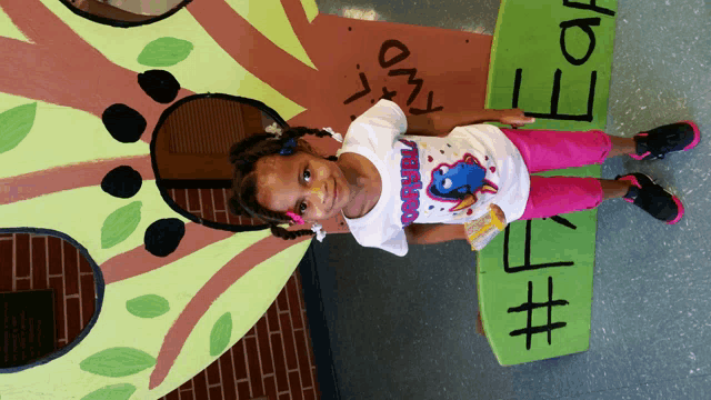a little girl stands in front of a sign that says " i am "
