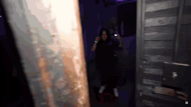 a woman standing in a dark room with an x on the bottom