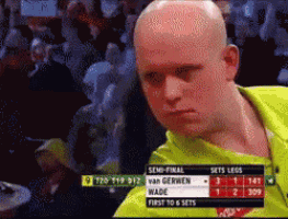 a bald man in a yellow shirt is watching a game on a television screen