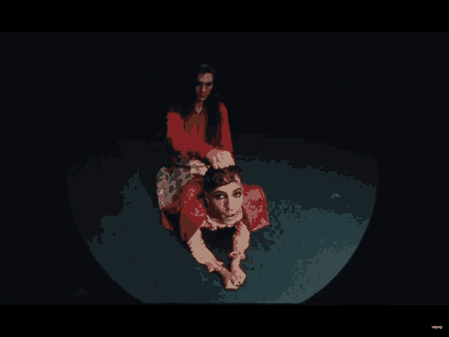 a woman in a red dress sits on a man 's back in a dark room